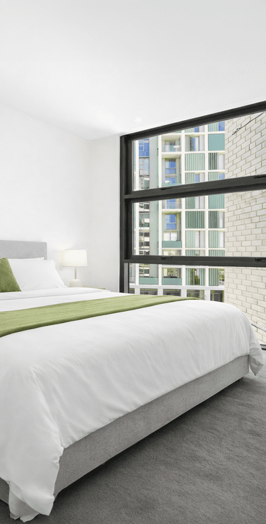 CityView 50mm Hook Awning Windows glazed full height in a bedroom, looking out to a brick and metal facade